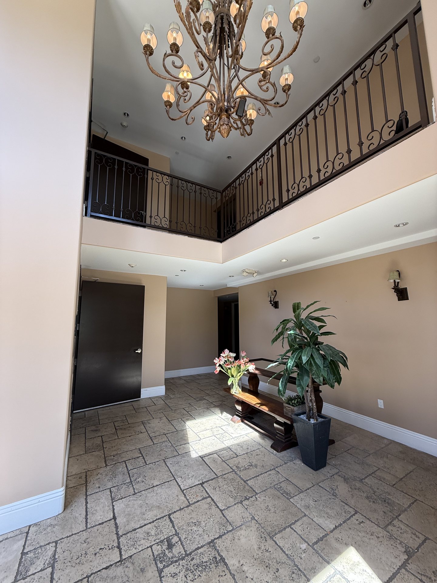 Double-height lobby foyer with chandelier and stone flooring