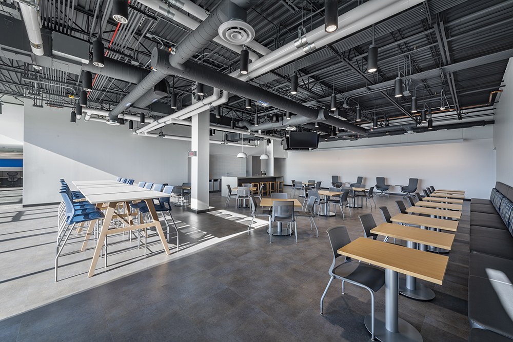Refinished break-room and dining area with new flooring, fresh paint, custom millwork counter, and furniture under an exposed ceiling, Culver City field service center fit-out by ASEP Contractors