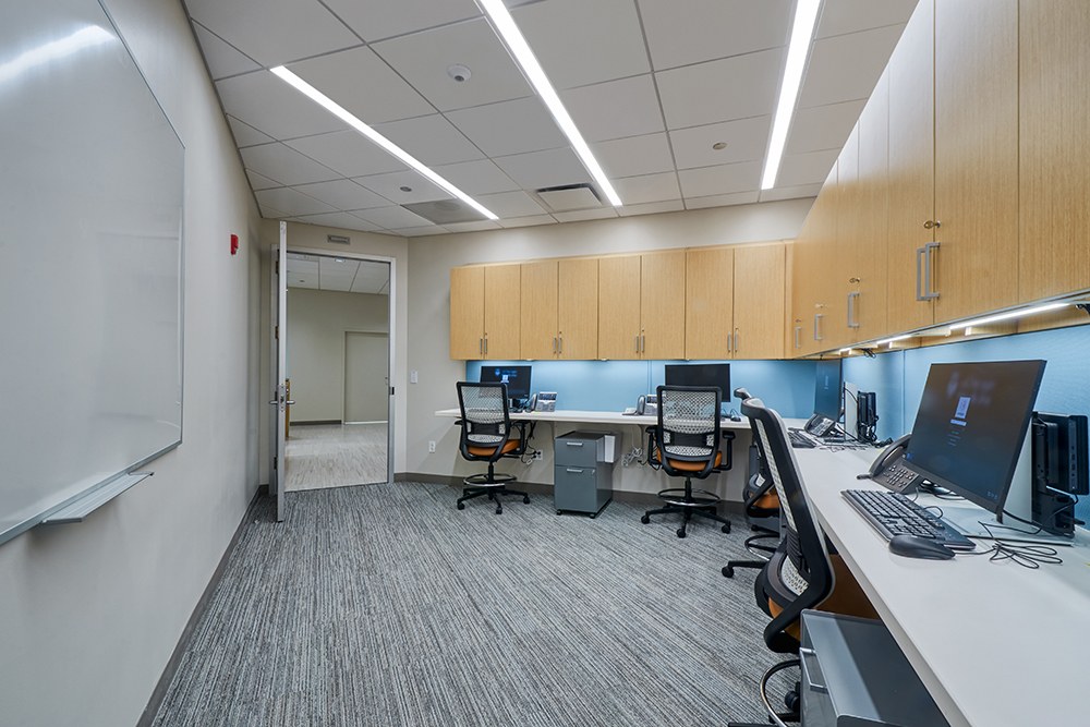 Medical office work room with built-in millwork cabinetry, workstations, task lighting, and new carpet, Brentwood renovation by ASEP Contractors