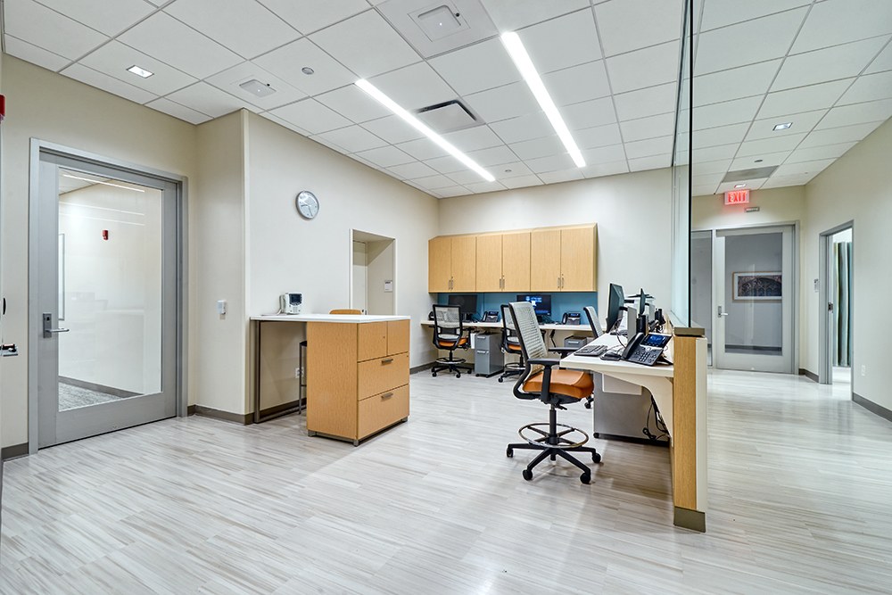 Open medical office area with light plank flooring, custom cabinetry, suspended T-bar ceiling, and workstations, Brentwood renovation by ASEP Contractors