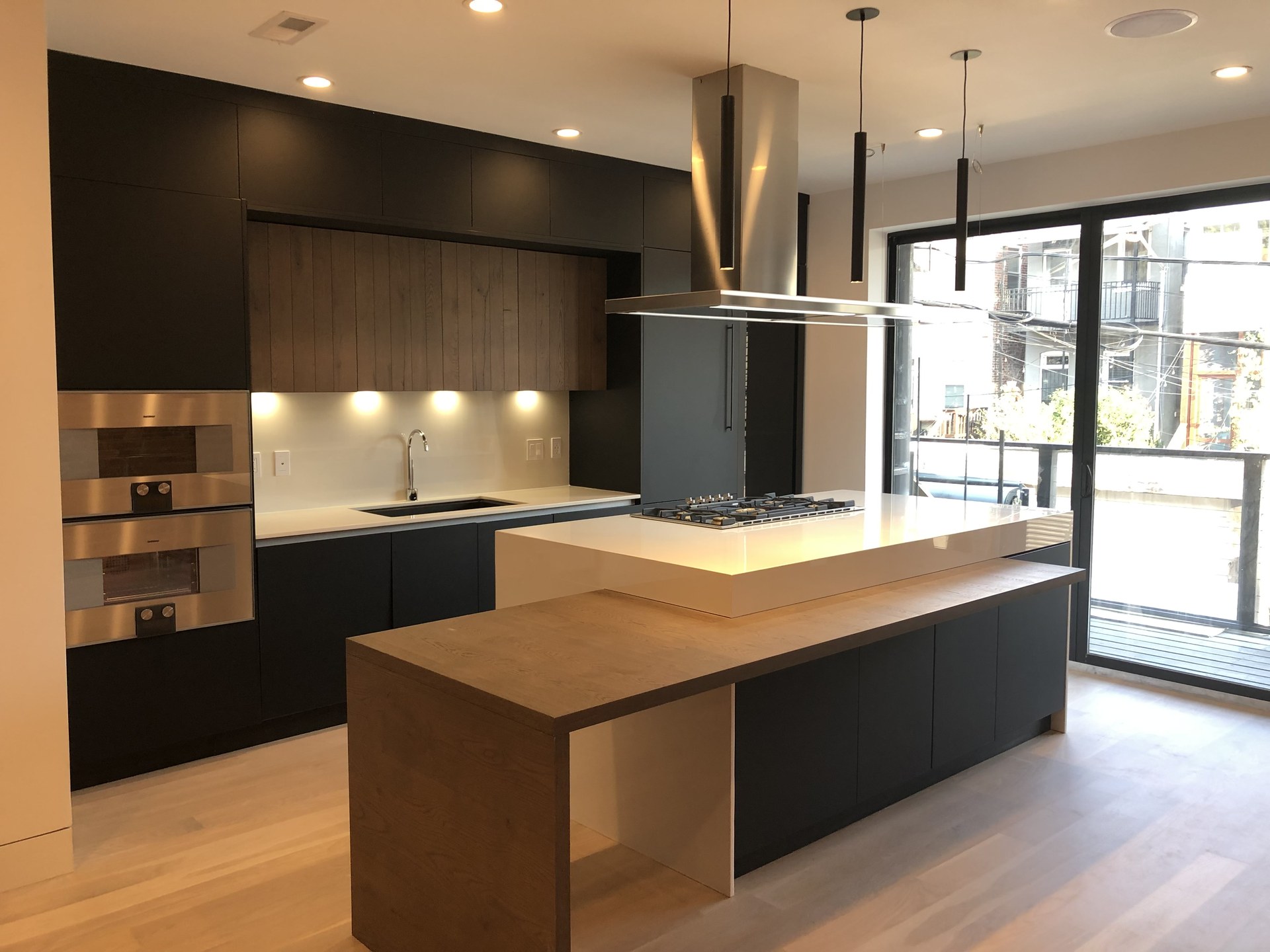 Dark contemporary kitchen with wood island and integrated appliances